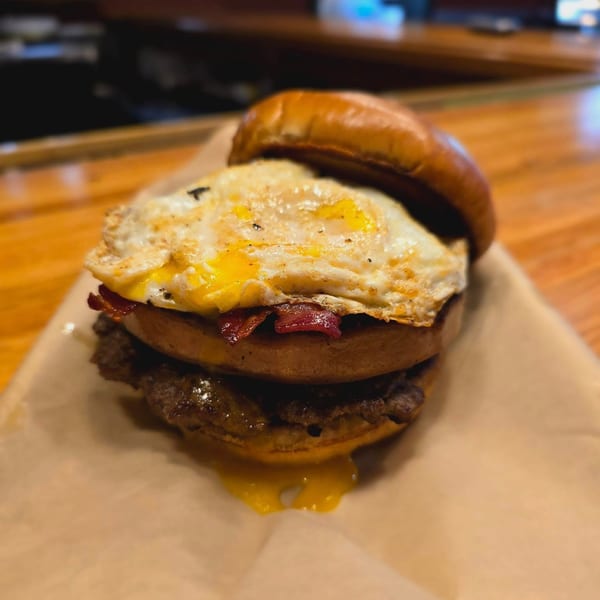 A juicy burger with bacon, a fried egg, and melted cheese on a bun.