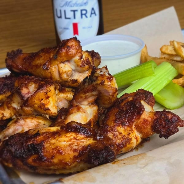 Cajun-spiced chicken wings with celery, fries, ranch, and a Michelob Ultra beer bottle.