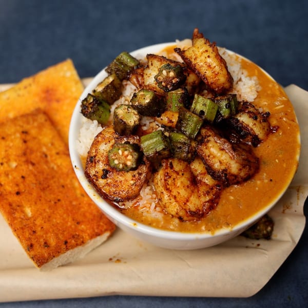 A bowl of Cajun shrimp and okra gumbo with rice, served with two pieces of toasted bread.